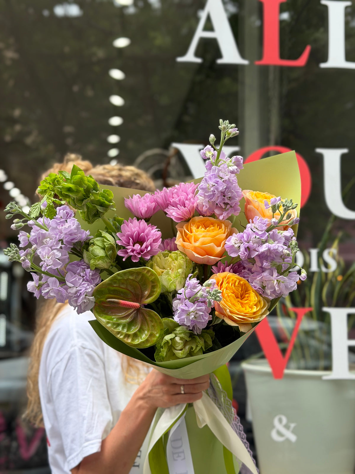 “Lavender Citrus Harmony” (Anthurium, Cream Garden Roses, Veggie Roses, Stocks, Bells of Ireland)