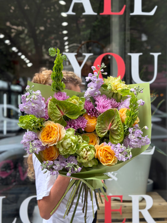 “Lavender Citrus Harmony” (Anthurium, Cream Garden Roses, Veggie Roses, Stocks, Bells of Ireland)